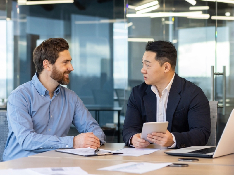 Two businessmen sitting at a desk for one-to-one English coaching English for Asia